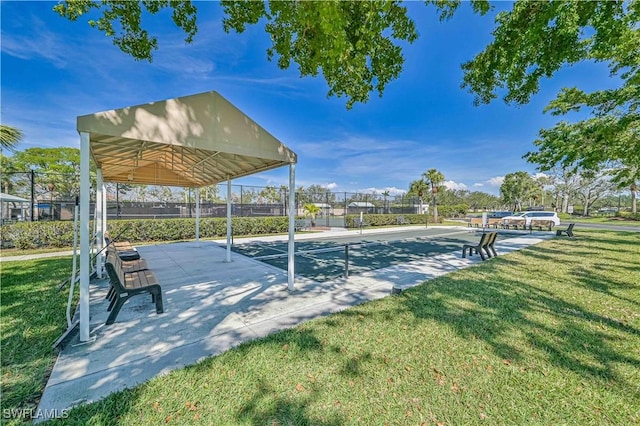 view of property's community with a yard, fence, and shuffleboard