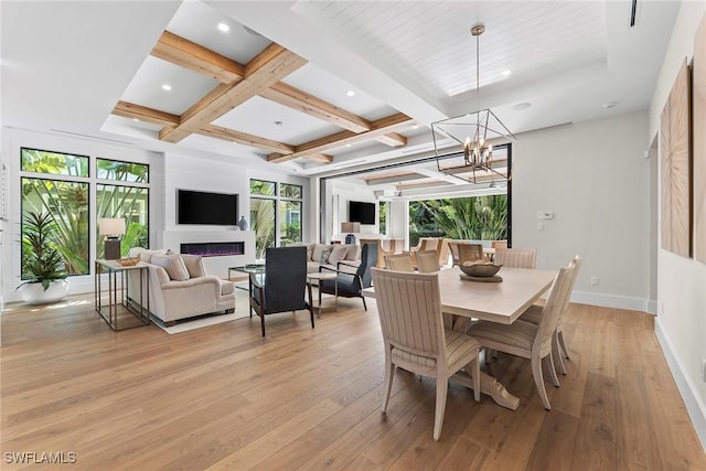 dining room with a warm lit fireplace, light wood-type flooring, beamed ceiling, and coffered ceiling