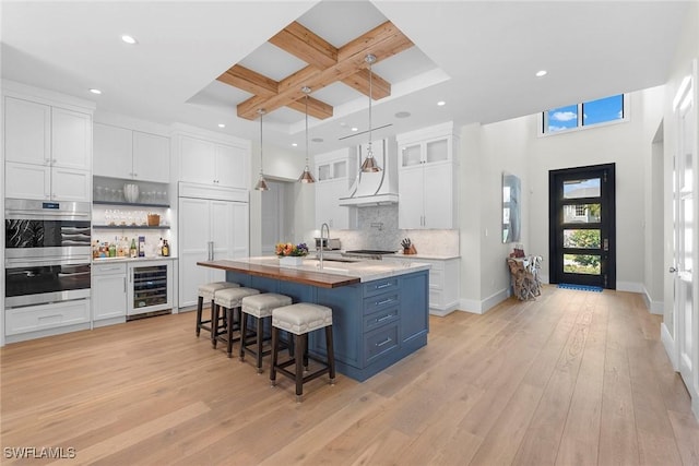 kitchen featuring wine cooler, double oven, white cabinetry, coffered ceiling, and paneled refrigerator