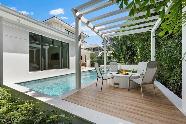 view of swimming pool with a fenced in pool, a fire pit, a wooden deck, and a pergola