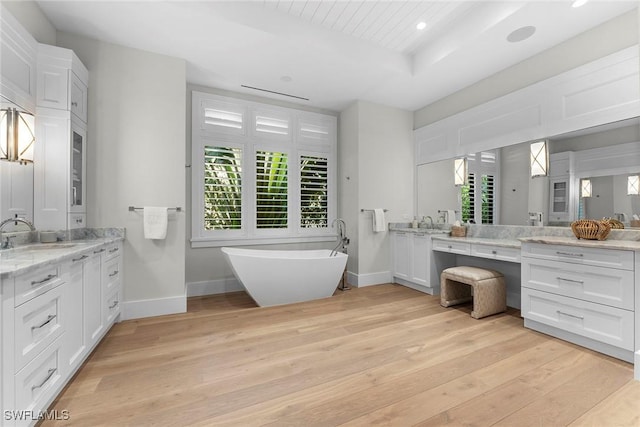 full bathroom featuring a wealth of natural light, a sink, a freestanding bath, and wood finished floors