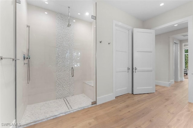 full bath with recessed lighting, tiled shower, baseboards, and wood finished floors