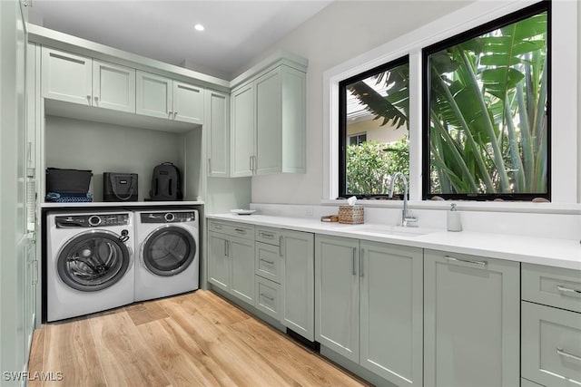 laundry area featuring cabinet space, washer and clothes dryer, light wood-style flooring, a sink, and recessed lighting