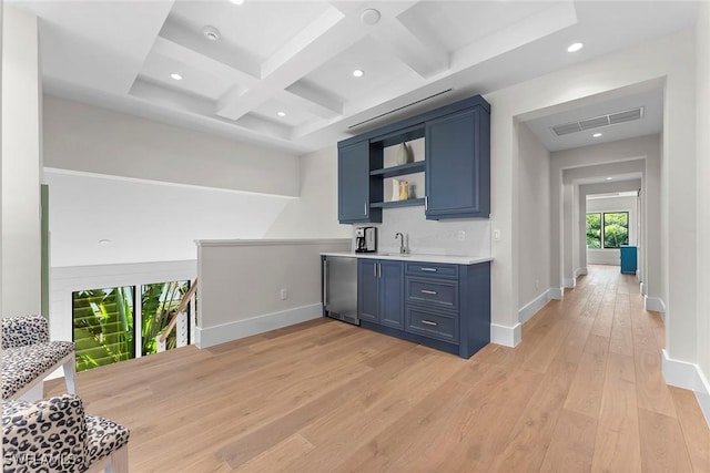 bar with light wood-style floors, coffered ceiling, a sink, and baseboards