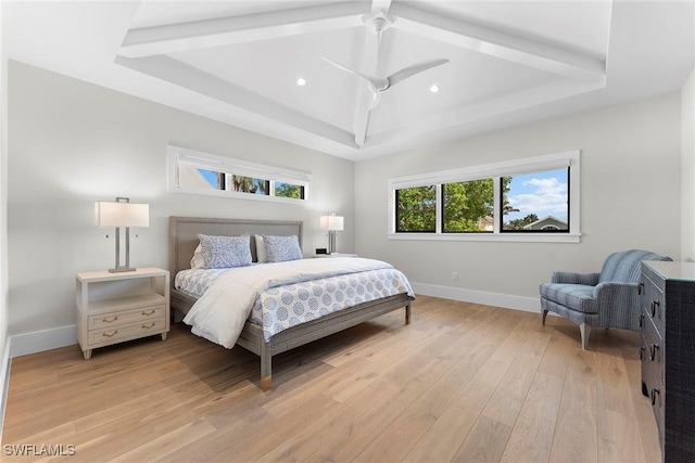 bedroom featuring light wood finished floors, a ceiling fan, baseboards, and a tray ceiling