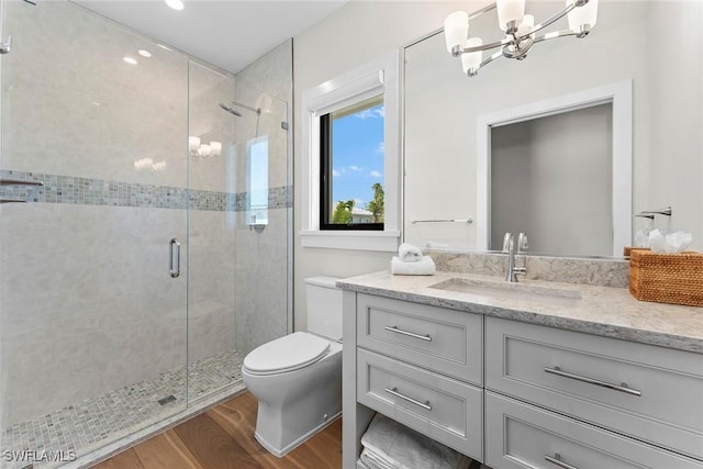 full bath featuring a stall shower, vanity, toilet, and wood finished floors