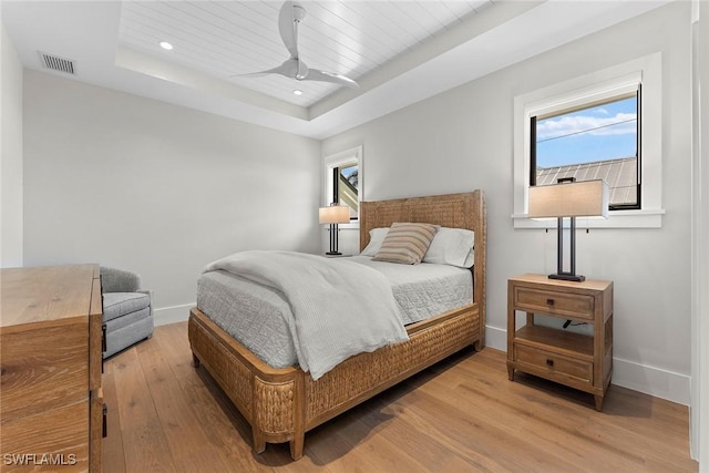 bedroom featuring recessed lighting, a raised ceiling, visible vents, wood finished floors, and baseboards