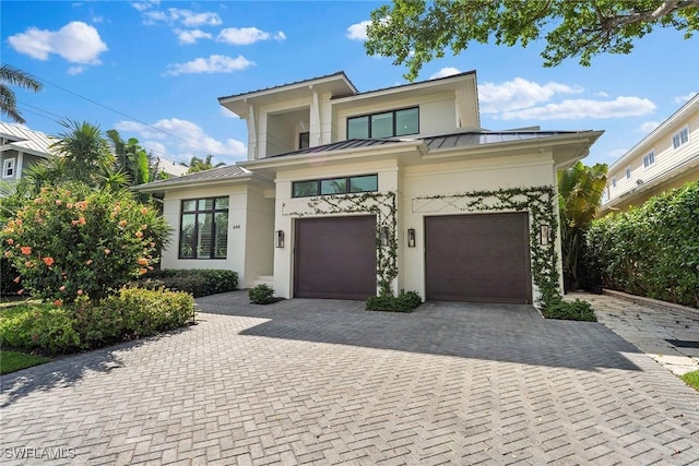 view of front of home with driveway, a standing seam roof, a garage, and metal roof