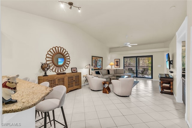 living area with vaulted ceiling, ceiling fan, and light tile patterned flooring