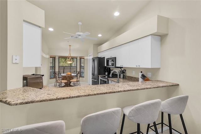 kitchen with recessed lighting, lofted ceiling, appliances with stainless steel finishes, white cabinets, and a peninsula