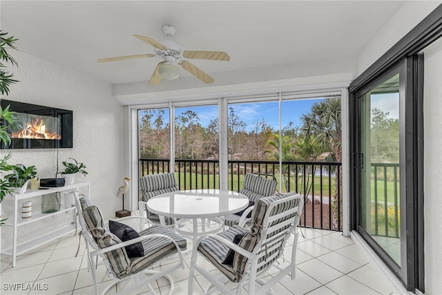 sunroom / solarium with a glass covered fireplace and a ceiling fan