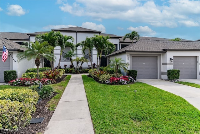 view of front of home with an attached garage, concrete driveway, roof with shingles, stucco siding, and a front lawn