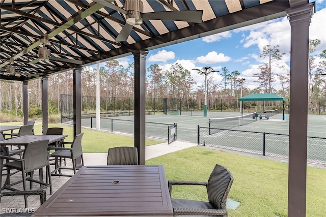 exterior space with a tennis court, outdoor dining space, and fence