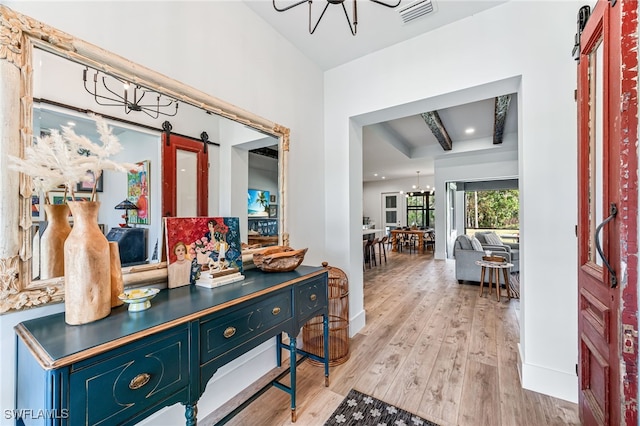 interior space with a chandelier, wood finished floors, visible vents, and a barn door