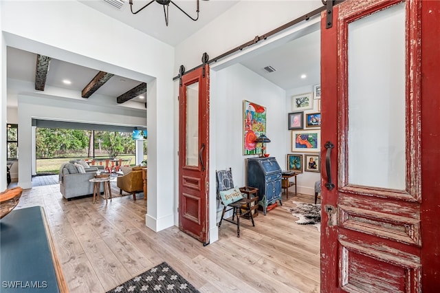 hall with light wood-type flooring, beamed ceiling, baseboards, and a barn door