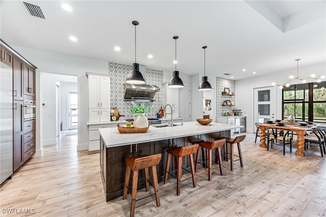 kitchen featuring light wood-style floors, light countertops, oven, and a sink