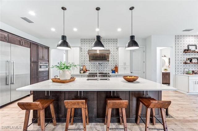 kitchen featuring light wood finished floors, visible vents, appliances with stainless steel finishes, and decorative backsplash