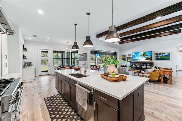 kitchen featuring light wood-style flooring, open floor plan, stainless steel appliances, dark brown cabinets, and a sink