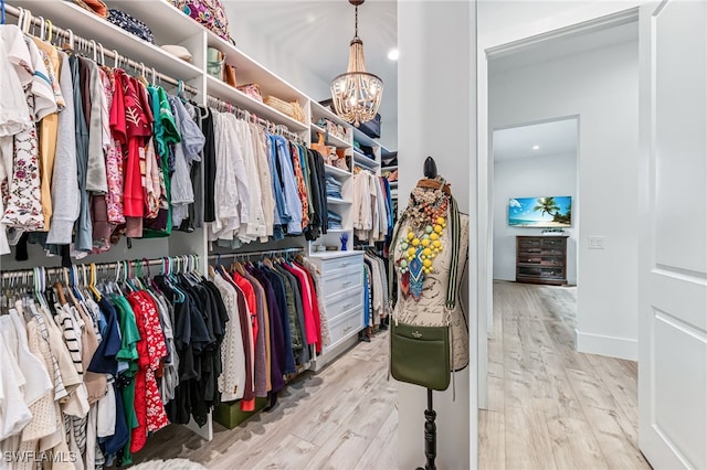 walk in closet with an inviting chandelier and wood finished floors