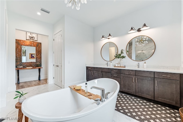 full bathroom with a freestanding tub, visible vents, a chandelier, and vanity