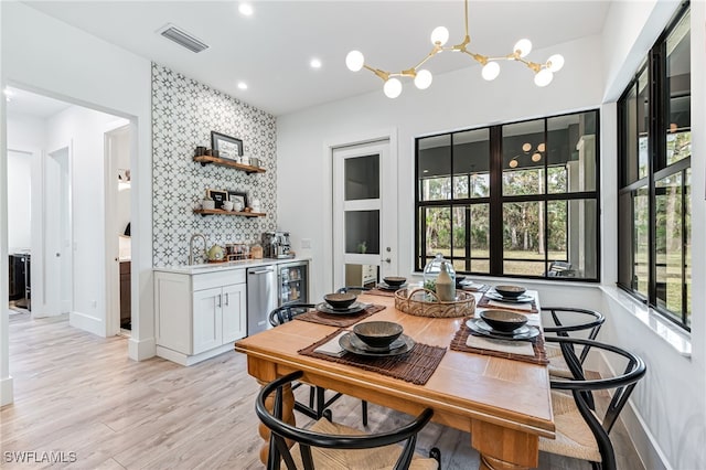 dining room featuring beverage cooler, visible vents, light wood-style flooring, an accent wall, and recessed lighting