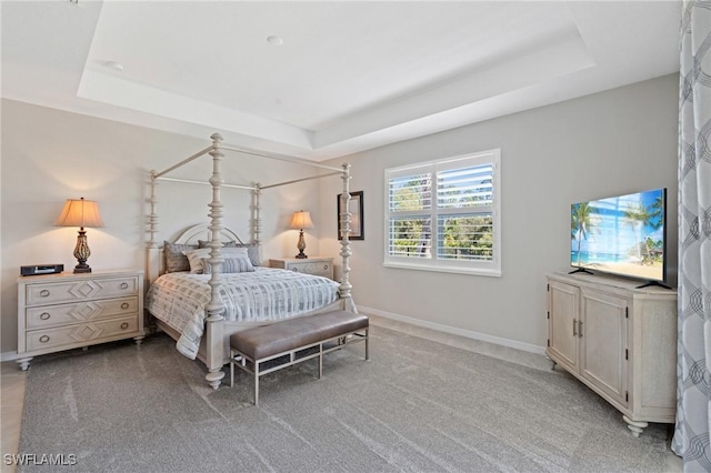 bedroom with a raised ceiling, light carpet, and baseboards