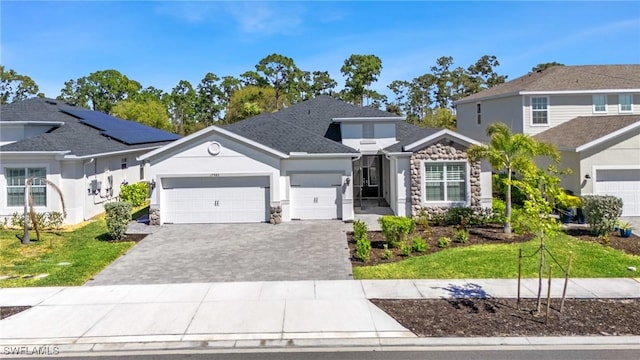 view of front facade with a garage, stone siding, decorative driveway, and stucco siding