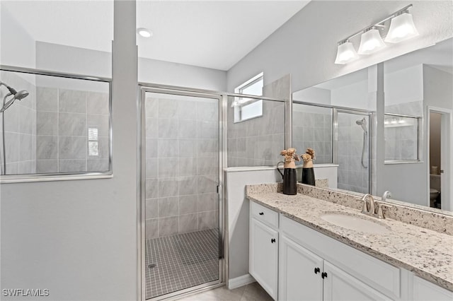 bathroom featuring toilet, a shower stall, vanity, and tile patterned floors