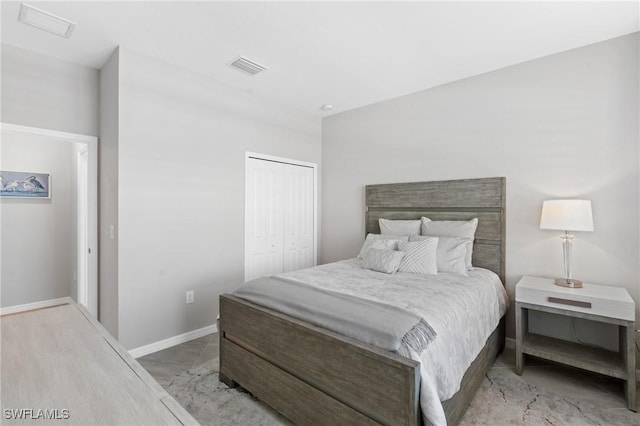 bedroom with baseboards, visible vents, and a closet