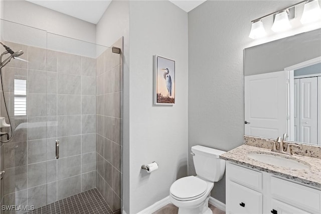 full bath featuring toilet, a stall shower, baseboards, and vanity