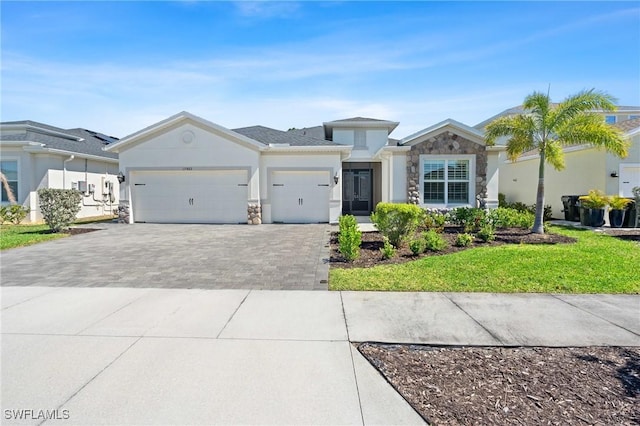 view of front of home with decorative driveway, stone siding, a garage, and stucco siding