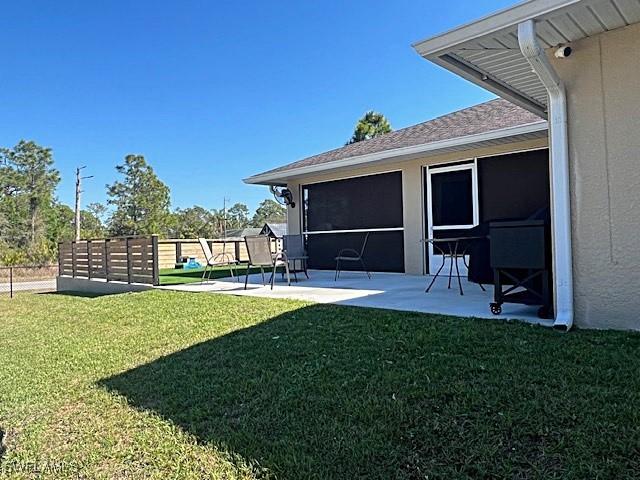 view of yard with a patio, fence, and a sunroom