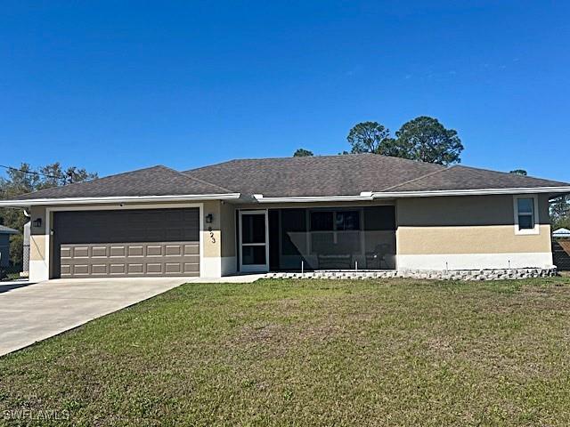 ranch-style house featuring a garage, a front lawn, concrete driveway, and stucco siding