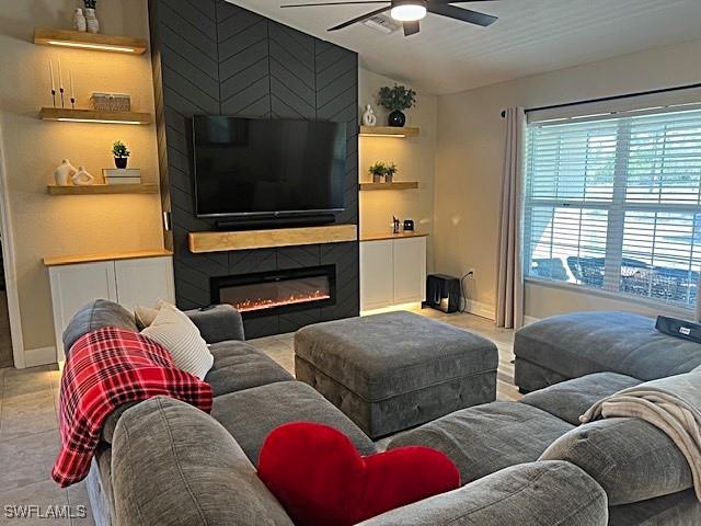 living area with a large fireplace, built in features, baseboards, ceiling fan, and vaulted ceiling