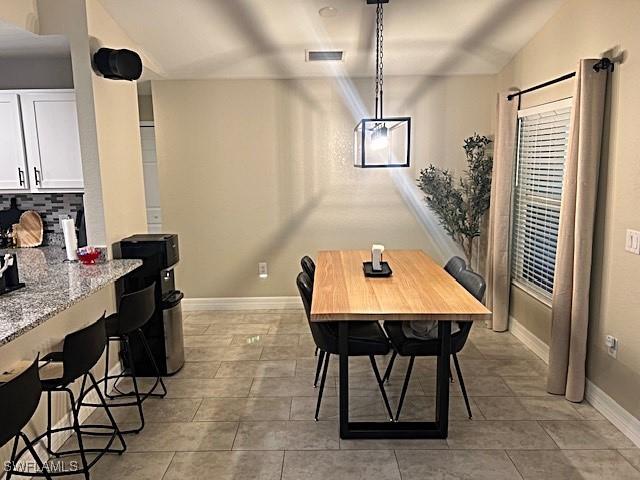 dining area with lofted ceiling, light tile patterned floors, visible vents, and baseboards