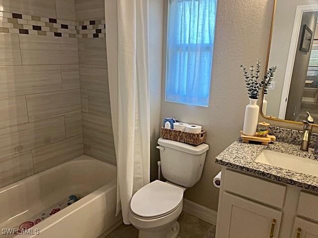 bathroom with baseboards, shower / tub combo with curtain, vanity, and toilet