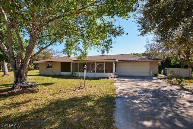 ranch-style house with driveway, a sunroom, an attached garage, a front yard, and stucco siding