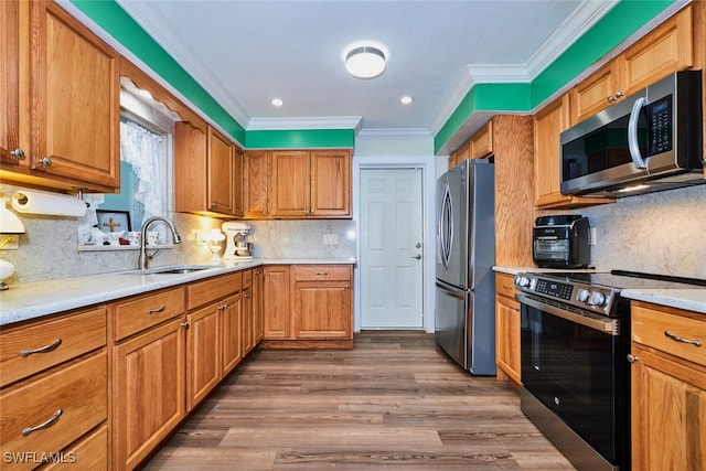 kitchen with dark wood-type flooring, stainless steel appliances, crown molding, light countertops, and a sink