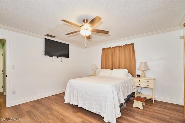 bedroom featuring a textured ceiling, ornamental molding, and wood finished floors