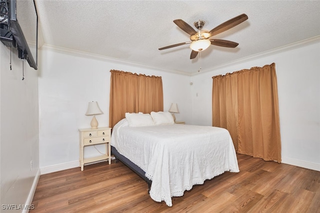 bedroom with ornamental molding, a textured ceiling, baseboards, and wood finished floors