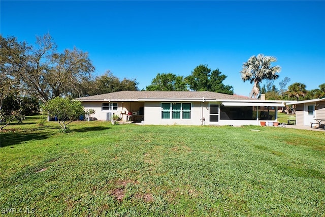 back of property featuring a sunroom, a yard, and stucco siding