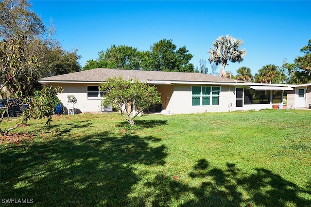 back of house featuring a lawn, a sunroom, and stucco siding