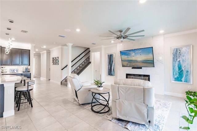 living area with ornamental molding, recessed lighting, ceiling fan, and stairway