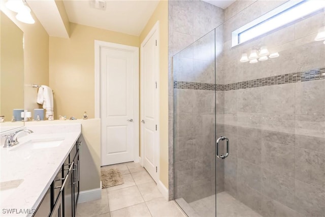 full bathroom featuring double vanity, a sink, a shower stall, baseboards, and tile patterned floors