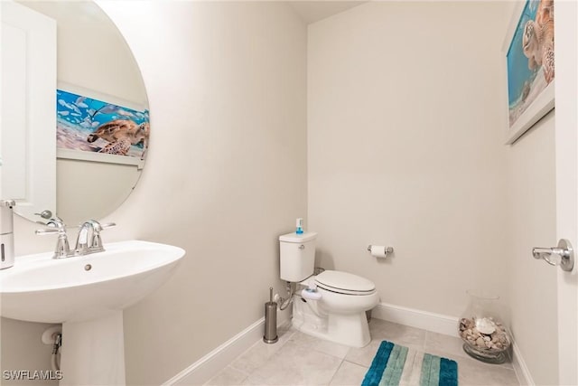 bathroom with toilet, tile patterned flooring, baseboards, and a sink