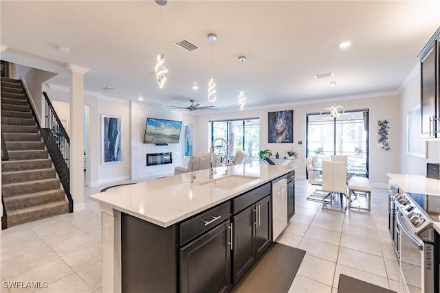 kitchen with light tile patterned floors, dishwashing machine, open floor plan, crown molding, and a sink