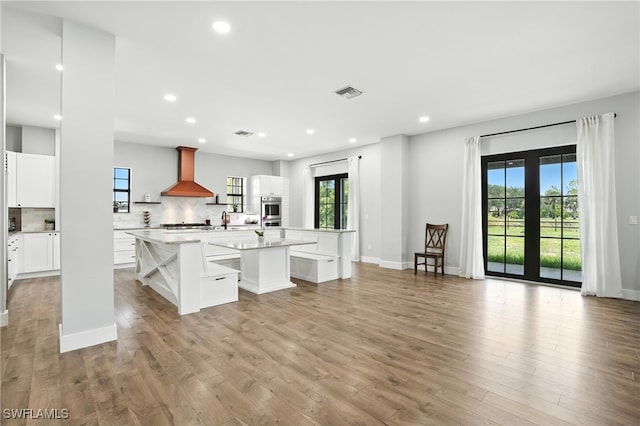 1474 Saint Clair Shores Rd, Naples, FL 34104 - kitchen with wall chimney range hood, a kitchen island with sink, recessed lighting, light countertops, and tasteful backsplash