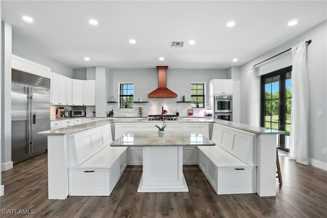 1474 Saint Clair Shores Rd, Naples, FL 34104 - kitchen featuring stainless steel appliances, a spacious island, wall chimney range hood, decorative backsplash, and dark wood-style flooring