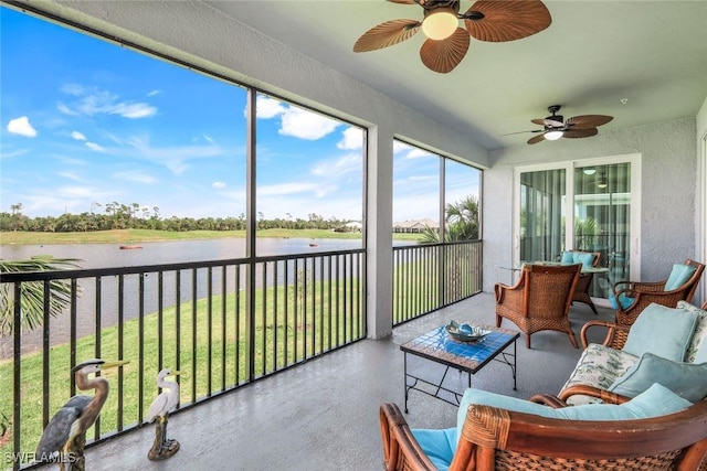 sunroom with a ceiling fan and a water view