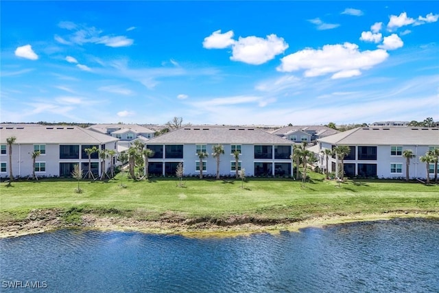 rear view of house with a yard, a water view, and a residential view